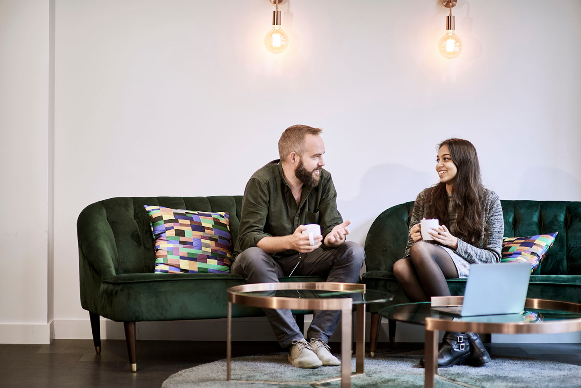 Two people having a discussion in an office together with a cup of tea. 