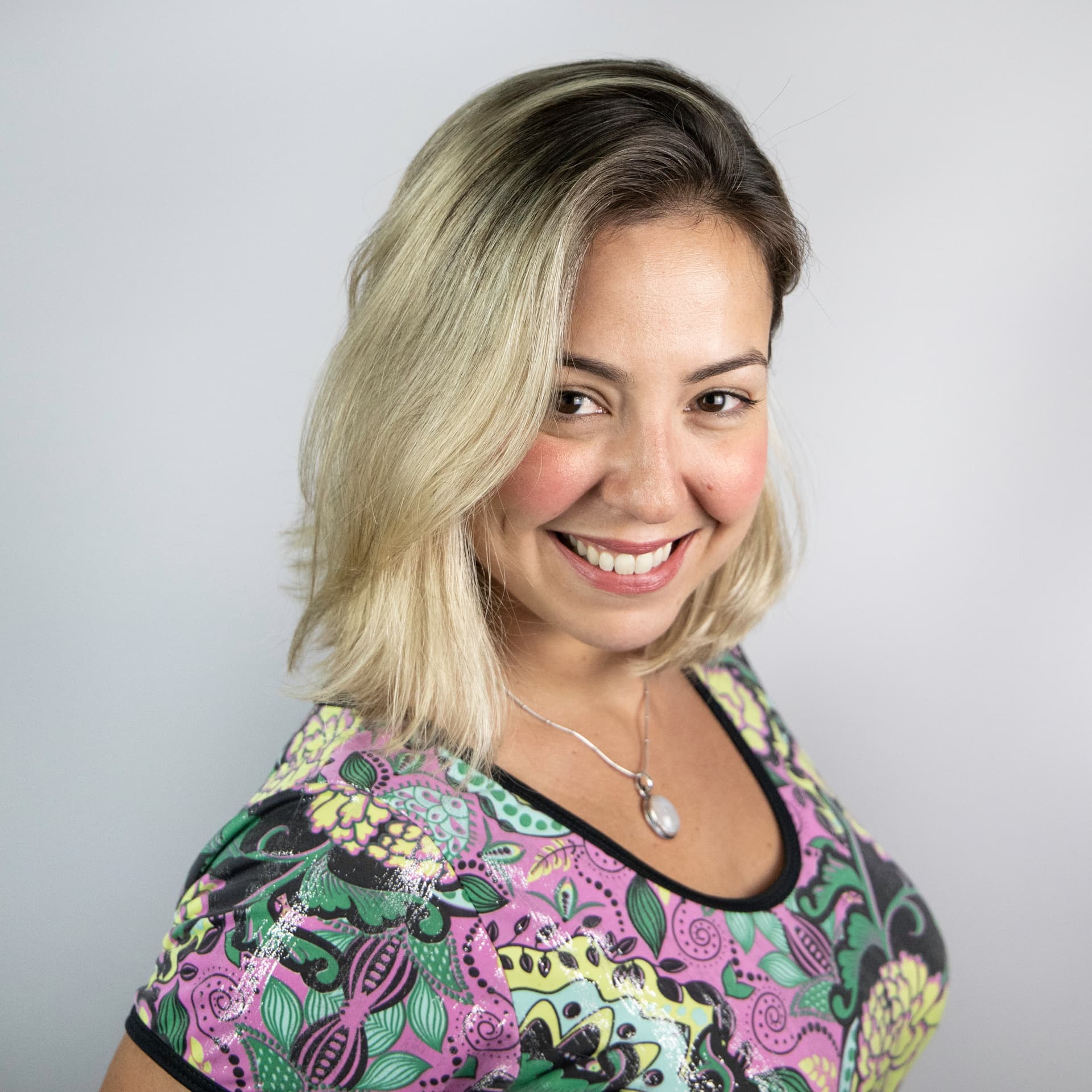 Carolina smiles at the camera, she is wearing a patterned top.