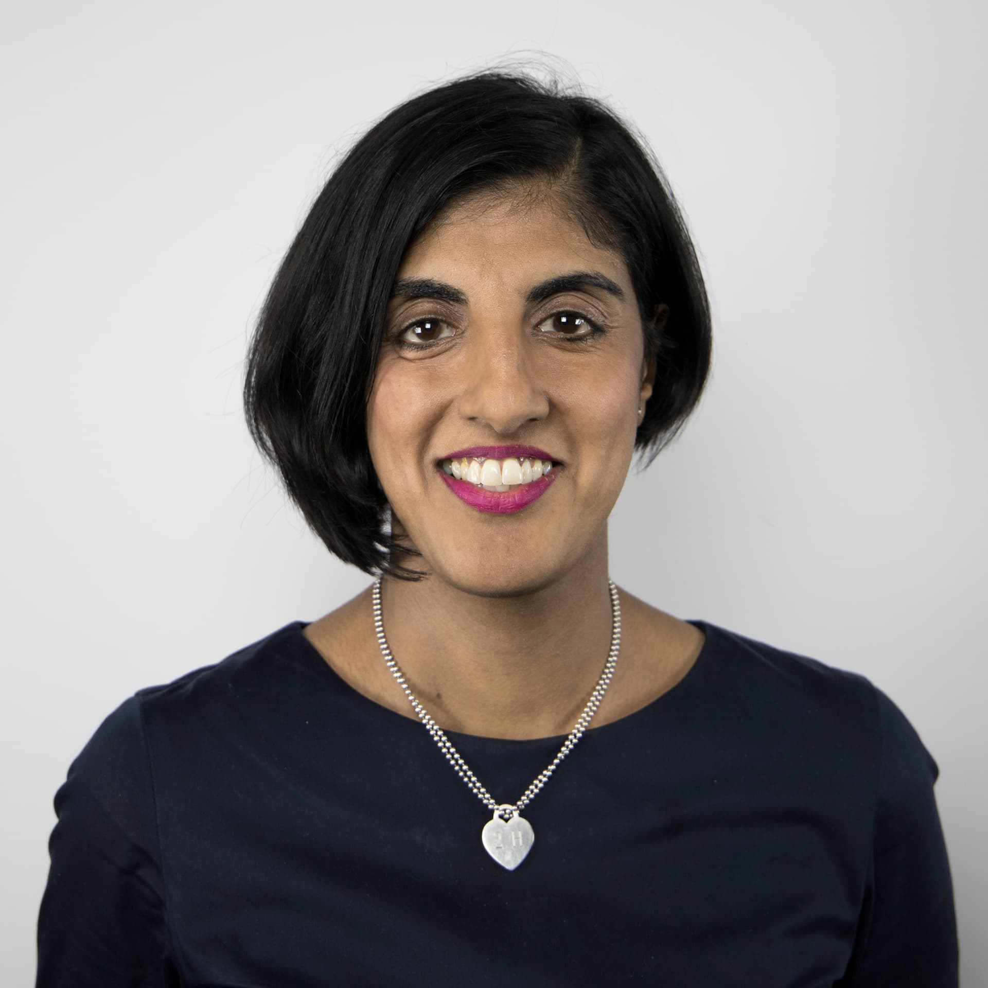 Harpal smiles at the camera. She is wearing a black top and a silver necklace.