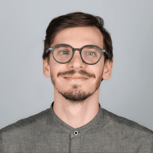 Alessandro smiles at the camera. He is wearing a grey shirt. Alessandro smiles at the camera. He is wearing a grey shirt.